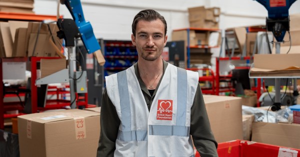 Brett Staniland in the British Heart Foundation eBay warehouse wearing a British Heart Foundation high-vis jacket.