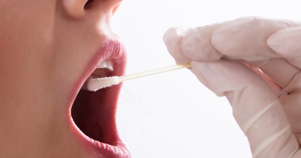 A gloved hand swabs the inside of a person's cheek