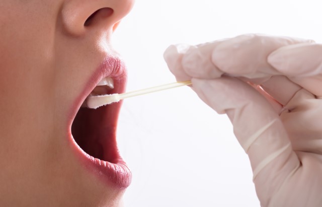 A gloved hand swabs the inside of a person's cheek