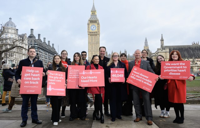 A group of BHF campaigners holding red signs with messages in white writing on them stand in front of Big Ben to campaign for heart disease to be made a priority