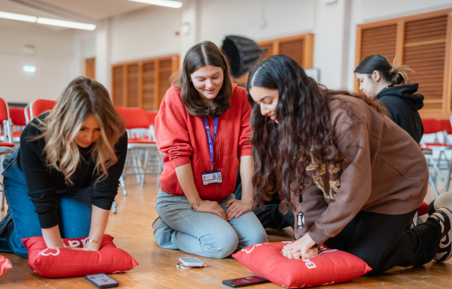 S Club and students learning CPR 