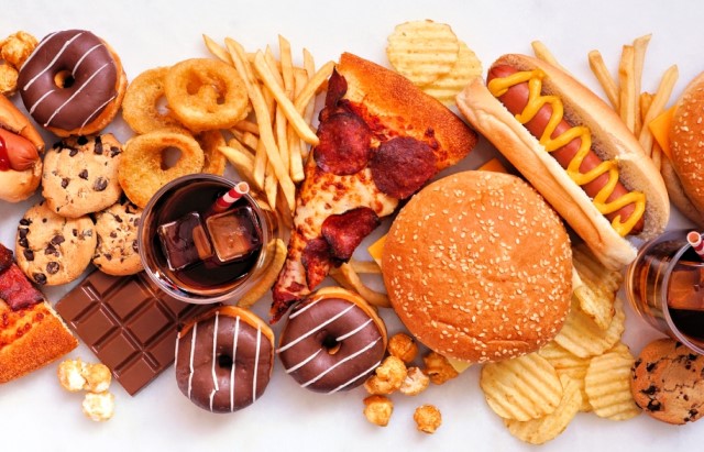 A selection of different processed foods including crisps, doughnuts, hot dogs, burgers, pizza and chocolate