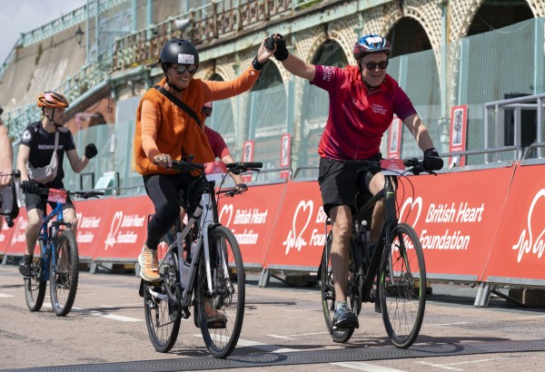 Patrick Vallance and wife Sophie cross the finish line on bikes at the 2024 London to Brighton Bike Ride 