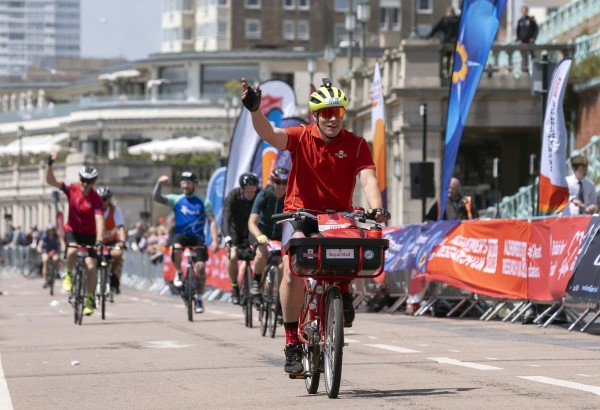 Postie James Trenchard crossing the finish line at London to Brighton on a vintage post bike 