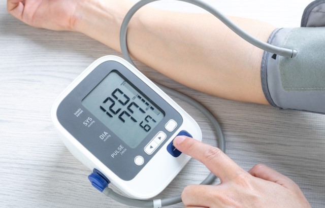 A person using a blood pressure monitor on their arm