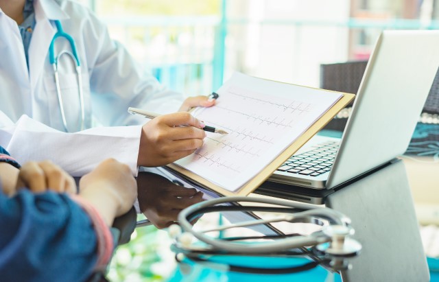 A doctor shows a patient ECG recordings on a piece of paper