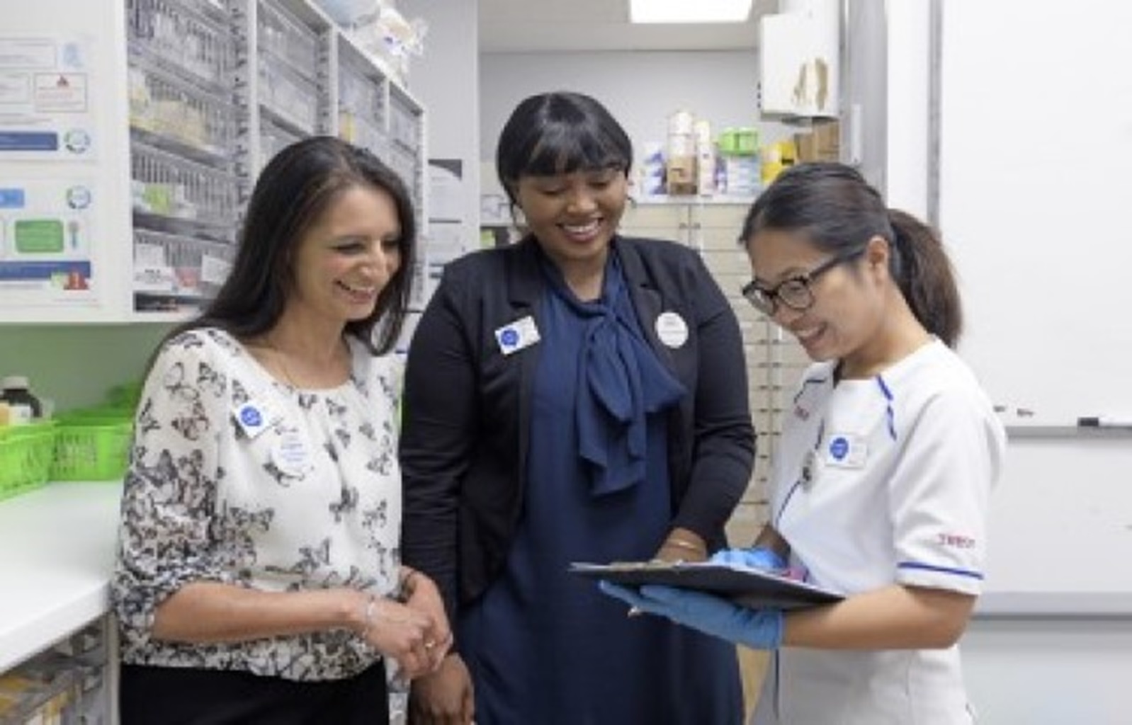 Three pharmacists reviewing clipboard