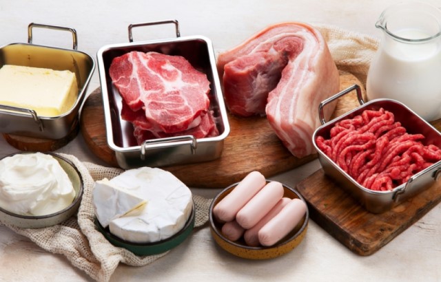 High saturated fat foods, including red meat, cheese and butter, arrange on a table