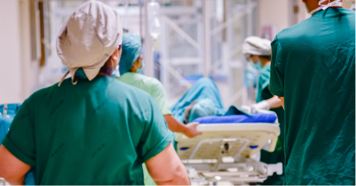 Two doctors walking in a hallway with a patient on a bed in front of them