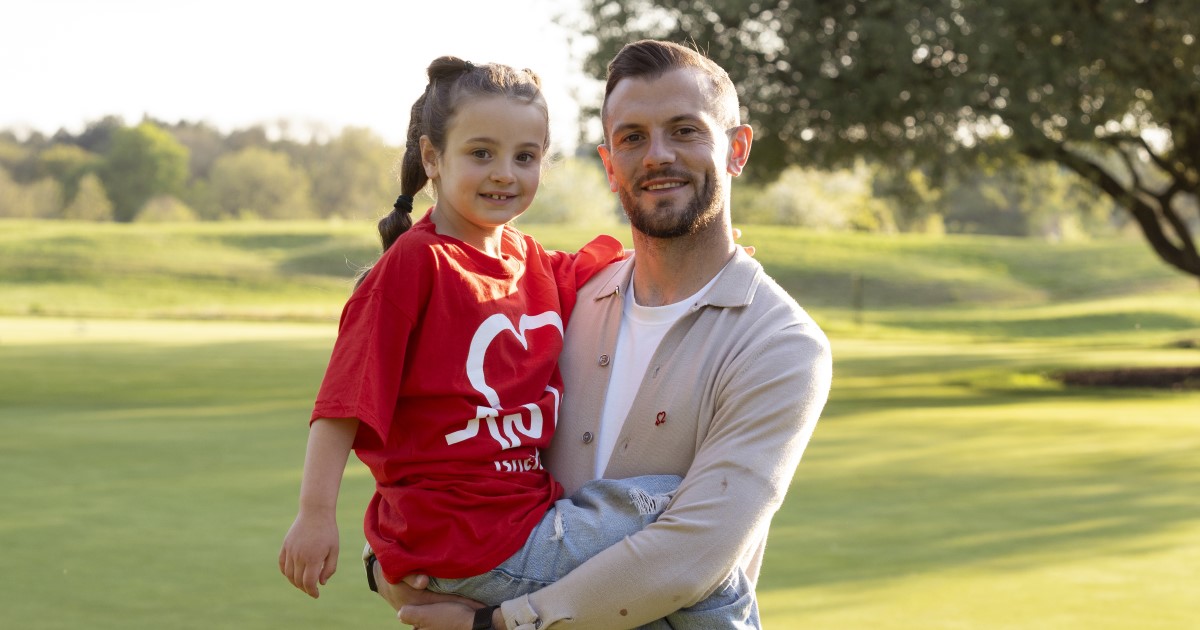 Photo of Jack Wilshere holding his daughter Siena, who is wearing a red BHF tshirt.