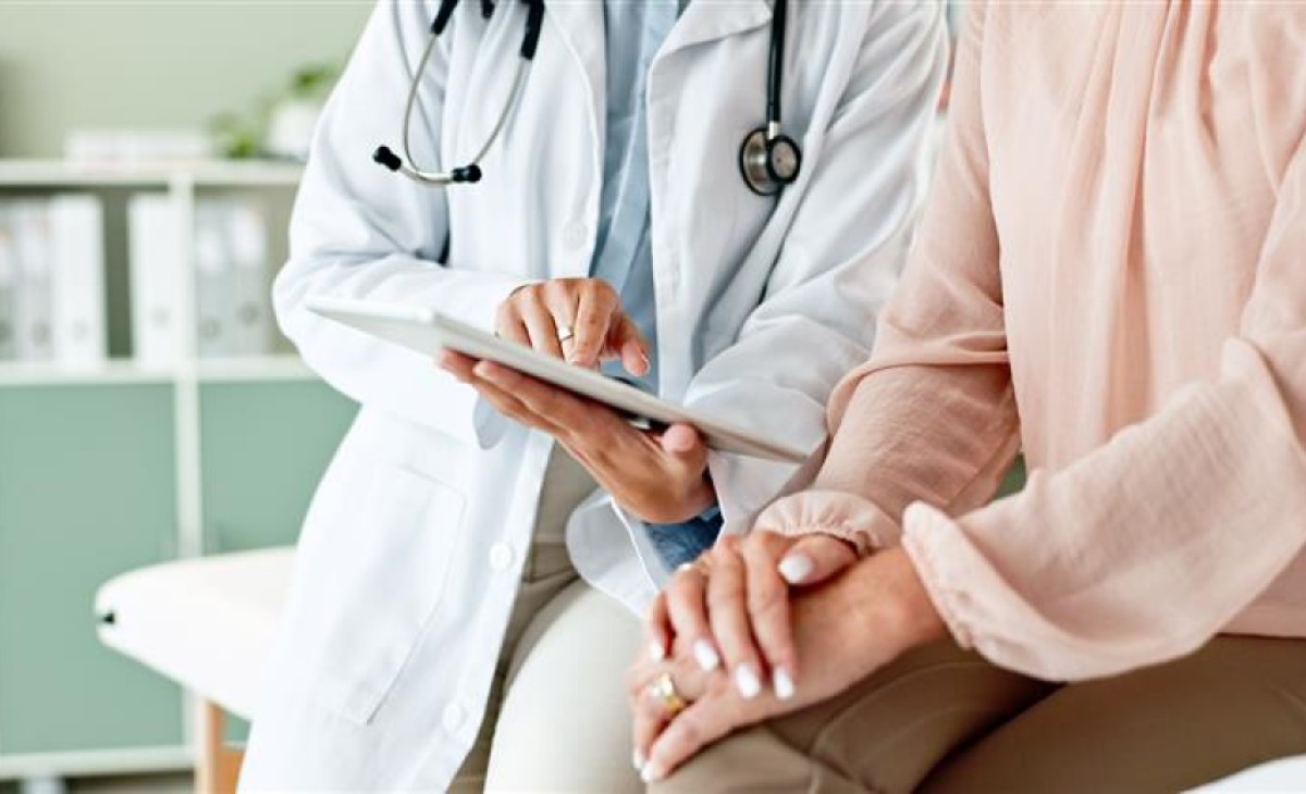 A doctor shows a patient something on a tablet 