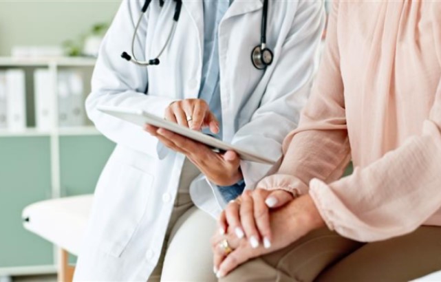 A doctor shows a patient something on a tablet 