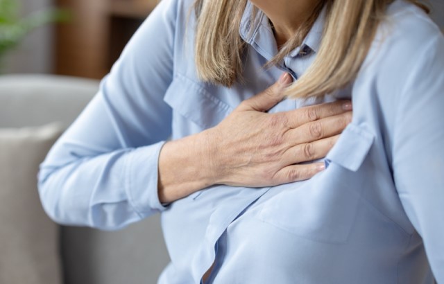 A woman holds a hand to her chest in pain