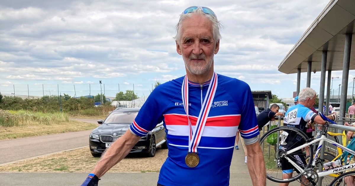 Photo of Brian Cookson standing behind his bike, he is wearing his cycling gear and has a medal around his neck.