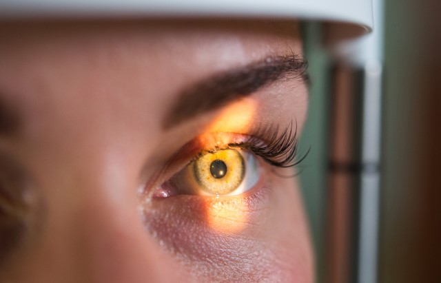 A woman's face is shown with light scanning across her eye 