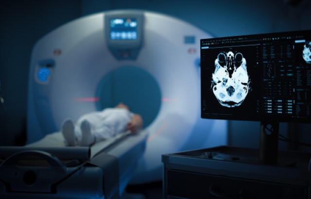 A person lies in an MRI scanner and a computer screen shows a scan image