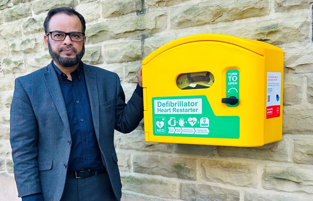 Man with hand on a defib on a wall