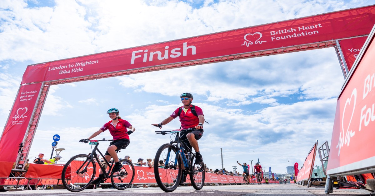 Woman and man crossing the finish line of London to Brighton on bikes