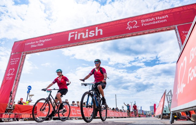 Woman and man crossing the finish line on bikes at London to Brighton Bike Ride