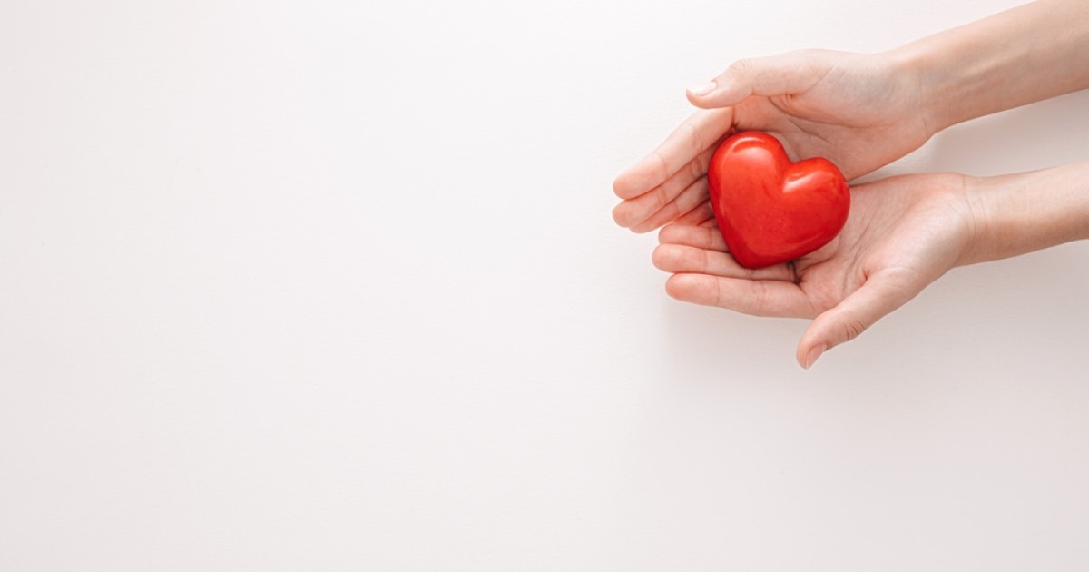 Two hands holding a red love heart