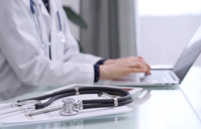 Person in lab coat sits at a computer