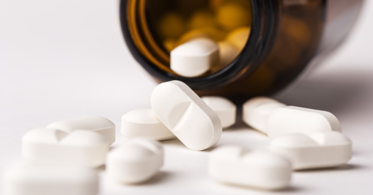 Supplement pills spill out of a brown bottle