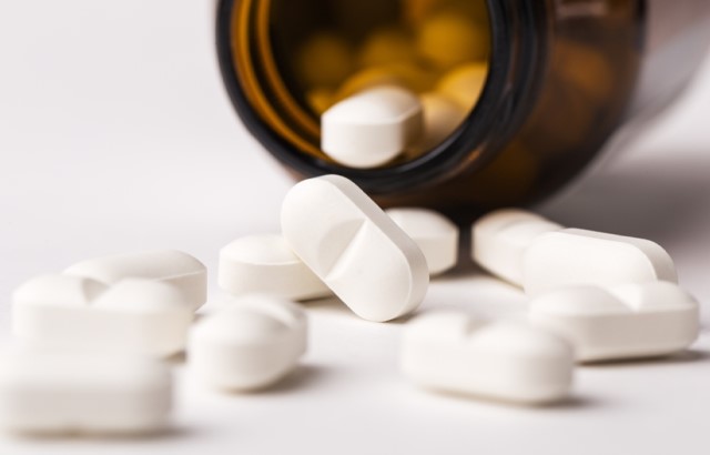 Supplement pills spill out of a brown bottle