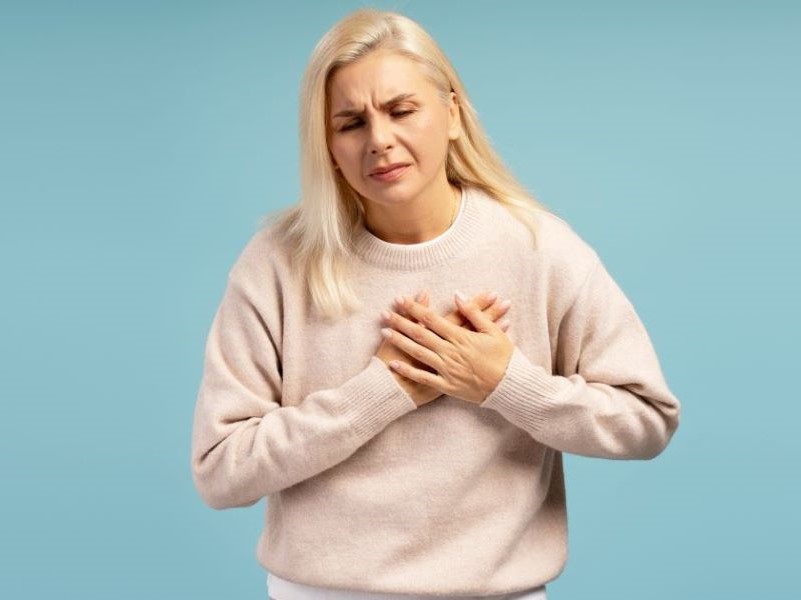 Woman clutches chest in pain