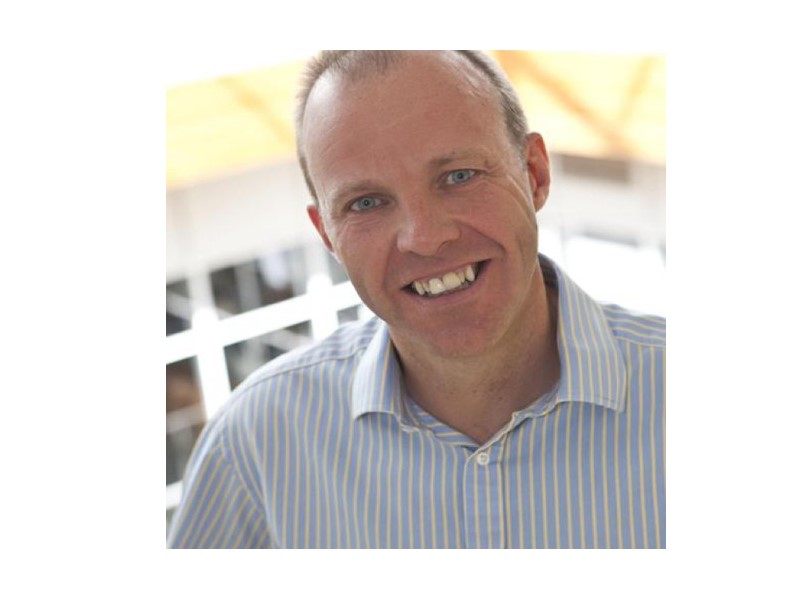 A picture of a smiling middle-age white man in a blue and white striped shirt