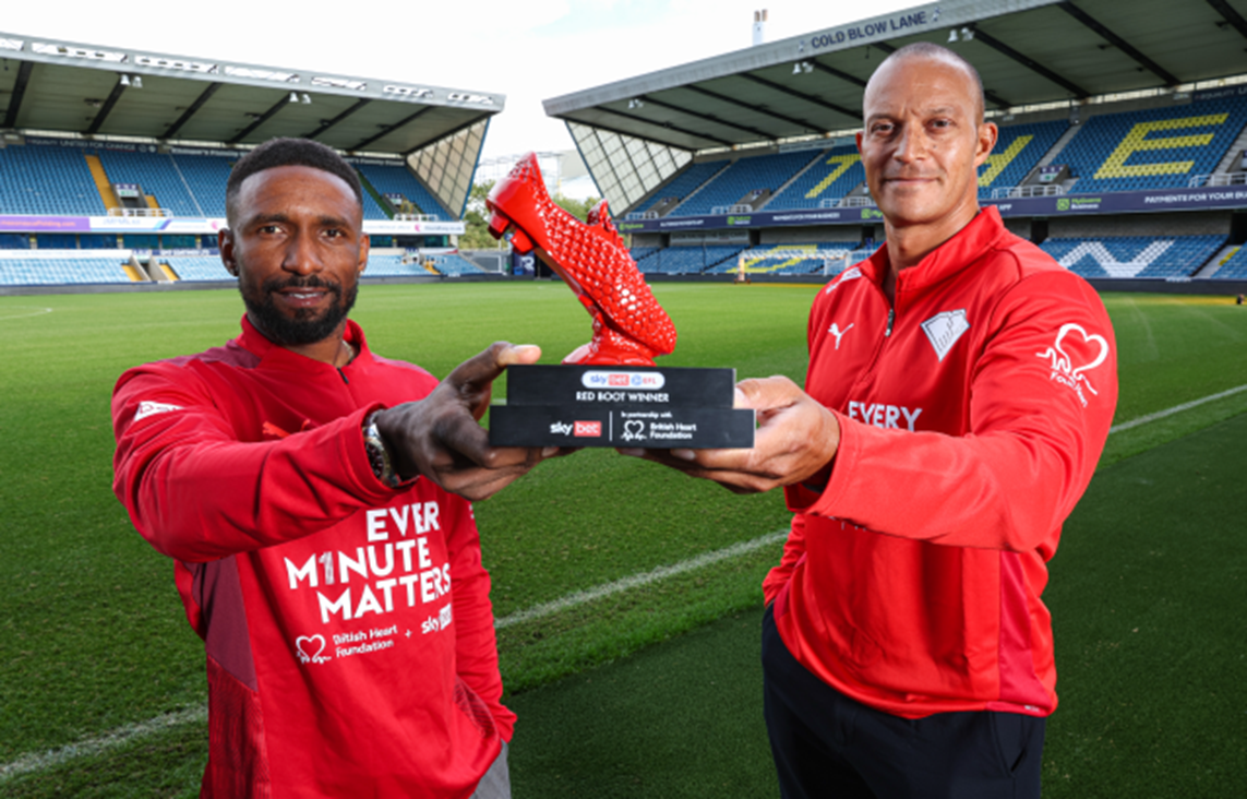 Jermain Defoe and Bobby Zamora holding trophy of a Red Boot with a football stadium in the background