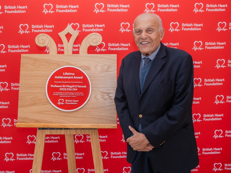 Professor Sir Magdi Yacoub stands next to his Lifetime Achievement Award plaque from the BHF