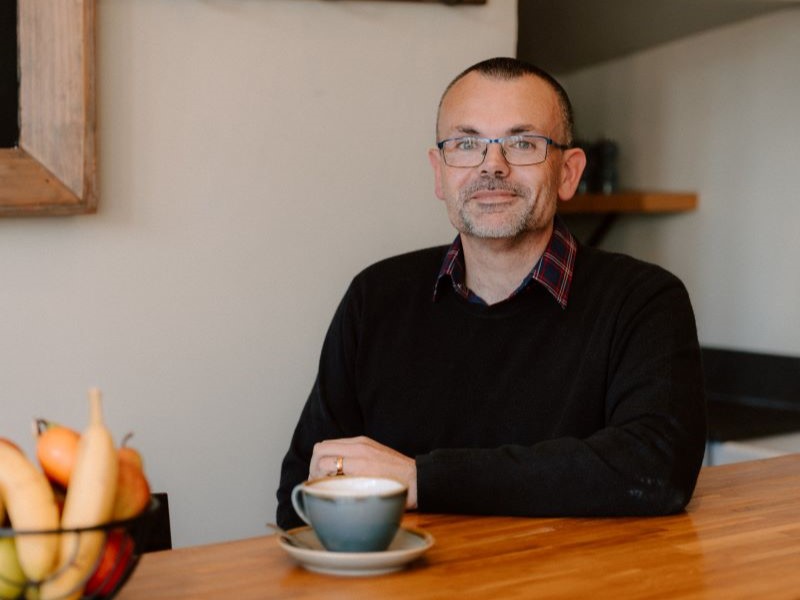 Ben Aitken sitting at a table with a cup of tea