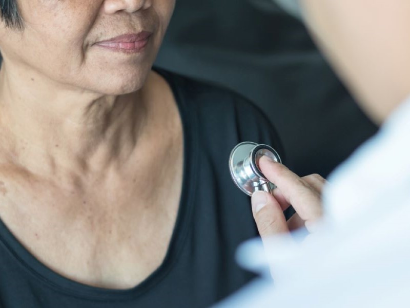 A doctor holds up a stethoscope to a woman's chest