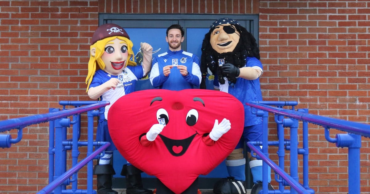 Image of Bristol Rovers mascots with Tom Lockyer and Hearty all holding Tom's special edition Panini card
