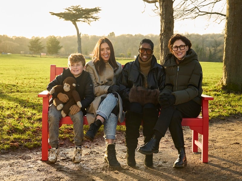 TV presenter Emma Willis sits on a BHF red bench with cardiovascular disease survivors Aimee and Leo Nicholls and Michelle White
