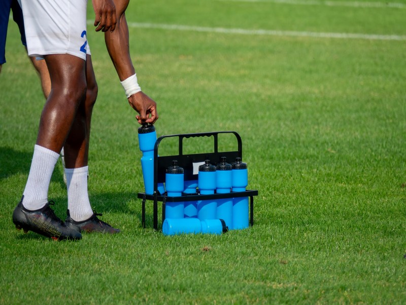 Sports water bottles on grass beside a player during a hydration break