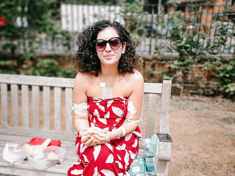Hannah Sharma during her hospital stay, sitting outside on a bench in the sun
