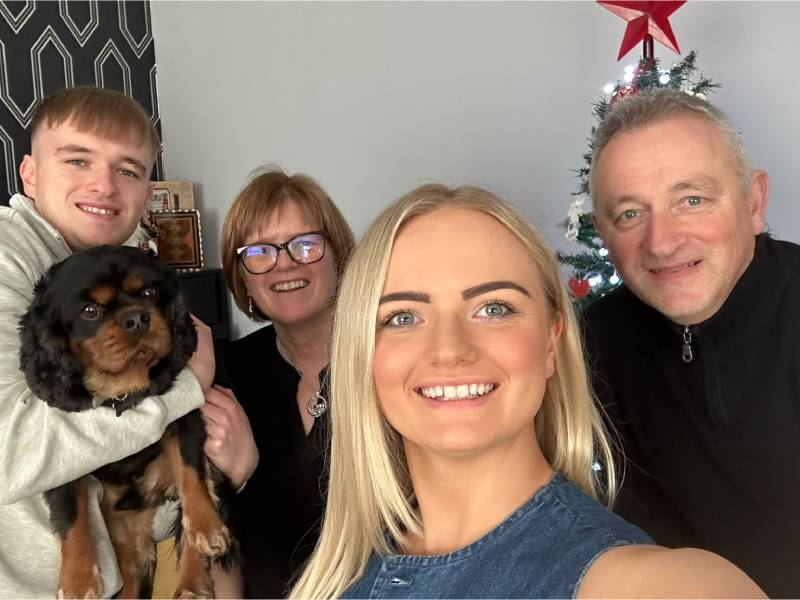 A family group with pet dog smile at the camera
