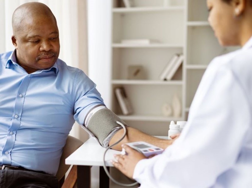 Image of a man with an arm cuff having his blood pressure taken by a doctor 