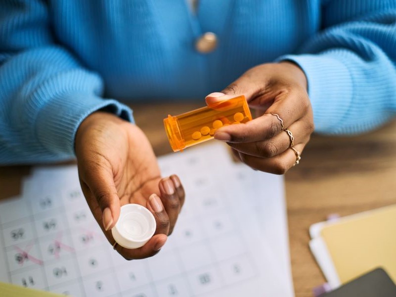 Image showing a woman tipping a bottle of pills into one hand 