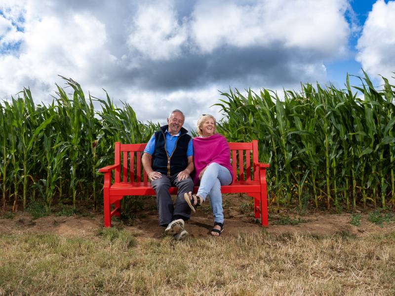 A man and a woman sit on a red bench