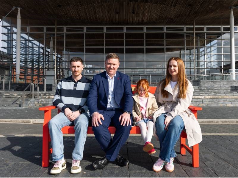 Two men and a woman sit on a bench with a small girl