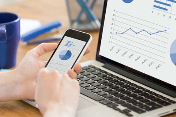 a man looking at data graphs on his laptop and smartphone