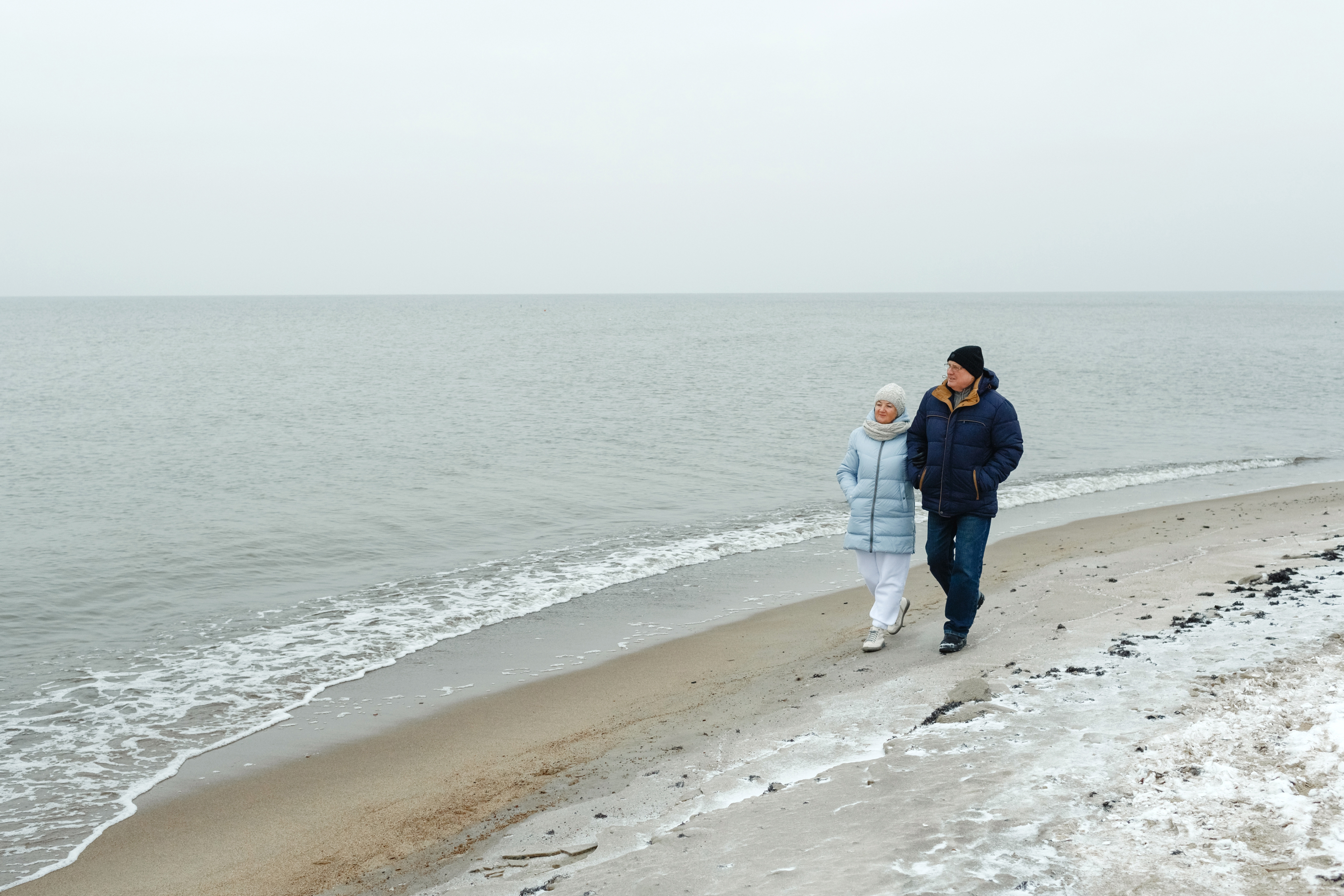 Elderly couple walking on beach in winter
